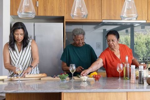 African american women preparing brunch at modern kitchen island with bread and wine