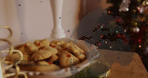 Festive cookies on scalloped porcelain pedestal with gold ribbon and bokeh lights