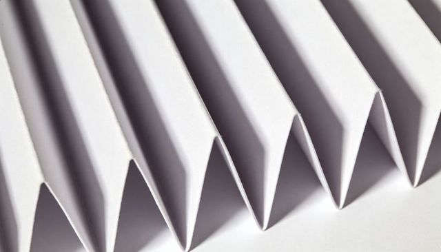 White accordion-fold paper creating sharp geometric zigzag pattern with dramatic shadows