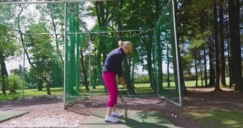 Senior woman practicing golf at outdoor driving range