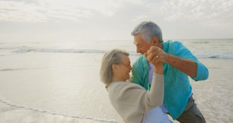 Elderly Couple Joyfully Dancing on a Sunny Beach Day