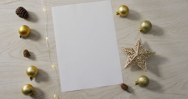 Blank Christmas card surrounded by gold ornaments, pine cones, and golden star decoration on wooden table. Useful for creating personalized holiday messages, festive invitations, or seasonal greeting cards.