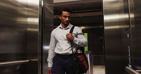 Business professional exiting elevator with glossy metal doors