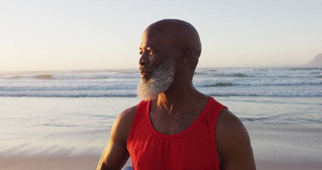 Smiling senior african american man walking at the beach. healthy outdoor leisure time by the sea.