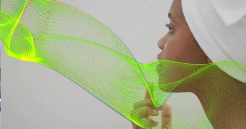 Contemplative woman in towel turban touching chin, serene profile with neon mesh accent