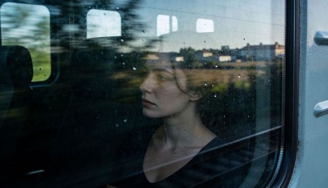 Gazing woman reflecting through rainy train window, contemplative travel portrait