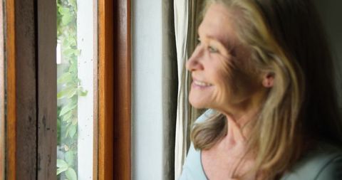 Senior Woman Gazing Peacefully Through Wooden Window
