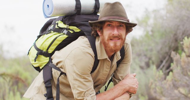 Portrait of happy bearded caucasian male survivalist with backpack, enjoying wilderness scenery. exploration, travel and adventure, survivalist in nature.