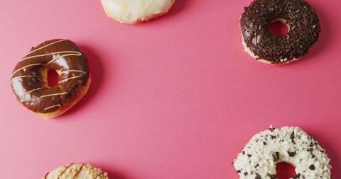 Colorful Assorted Donuts with Icing on Pink Background