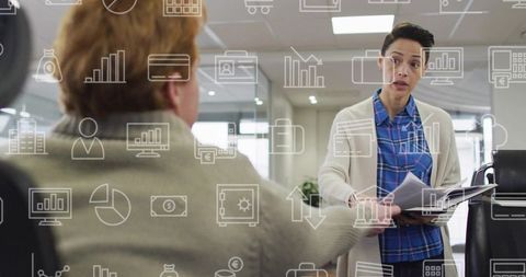 Colleague passing documents to seated coworker during consultative office collaboration