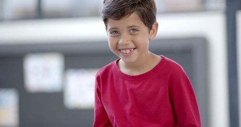 Young Boy in Classroom Wearing Red Shirt Looking Down with Focus