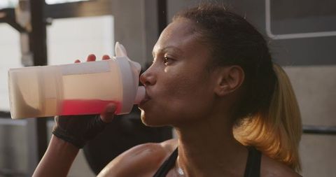 Athletic woman drinking hydration shake at gym