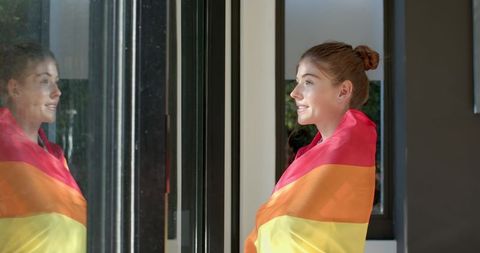 Serene Woman Wrapped in Rainbow Pride Flag Viewing Garden