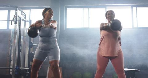Diverse mid-adult women performing kettlebell swings building strength and teamwork