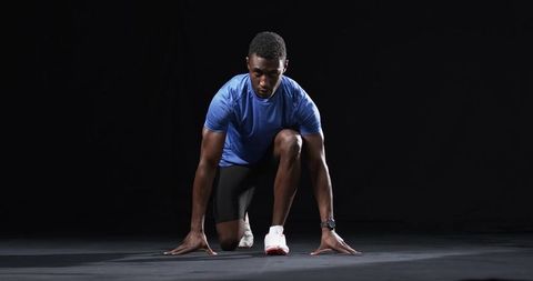 Determined Male Athlete Preparing to Sprint on Track