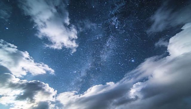 Milky Way Arch Over Luminous Clouds Night Sky Filled with Stars and Cosmic Glow