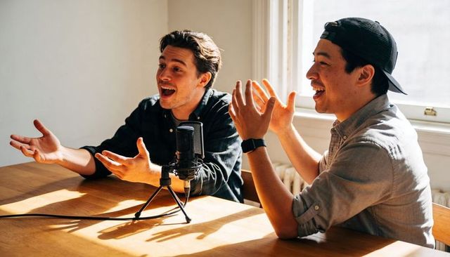 Recording conversational podcast two hosts at sunlit wooden table