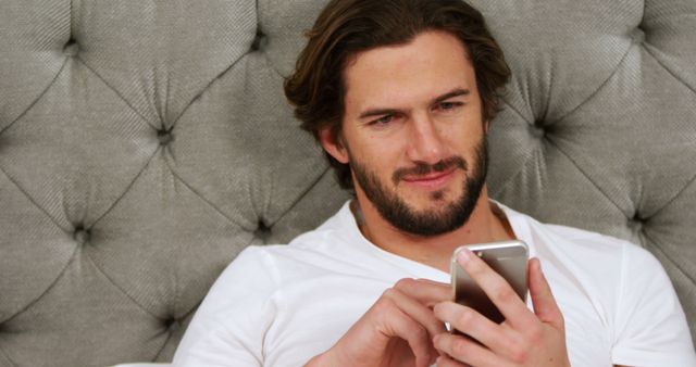 Man using mobile phone in bedroom at home