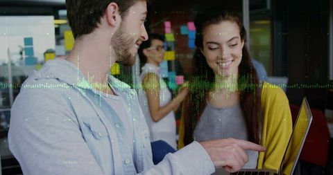 Young professionals collaborating on laptop with notes and waveform overlay for innovation