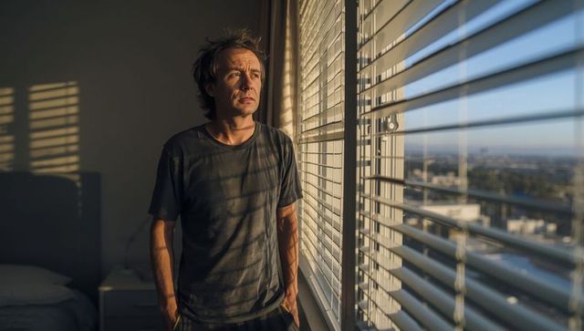 Thoughtful Man Staring Out of Window in Sunlit Room