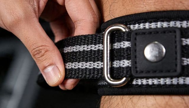 Adjusting black woven wrist strap with metal d-ring close-up highlighting weave and hardware