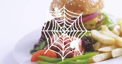 Halloween burger plate featuring spiderweb overlay, fries and fresh salad closeup