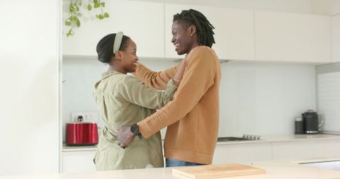 African American couple embracing and smiling in modern bright minimalist kitchen