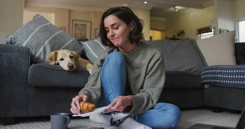 Woman relaxing with breakfast and dog in cozy living room