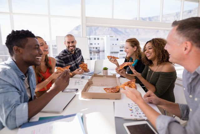Happy executives sharing pizza in conference room at office