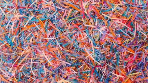Overhead video of multicolored shredded paper pile showing curled strips, texture, and motion