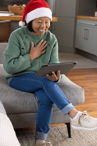 Senior Woman in Santa Hat Using Tablet for Festive Video Call