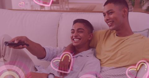 Happy Biracial Gay Couple Watching Television with Heart Icons Overlay