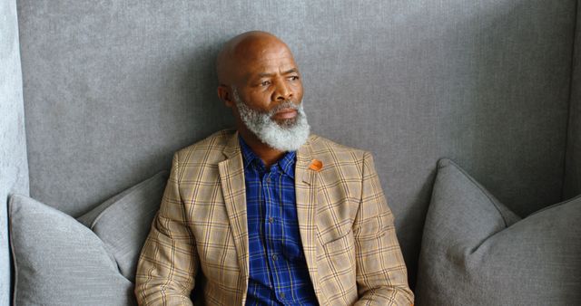 Mature Man with Beard Sitting on Gray Couch Looking Thoughtful - Download Free Stock Images Pikwizard.com