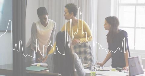 Women collaborating over data-driven strategy with laptop and line chart in modern office
