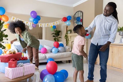 African american family celebrating birthday with balloons, gifts, joyful living room party
