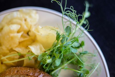 Crunchy potato chips paired with fresh pea shoots and artisan sourdough bun close-up