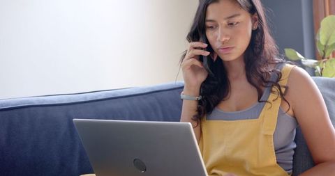Teen Girl Using Laptop and Talking on Smartphone at Home