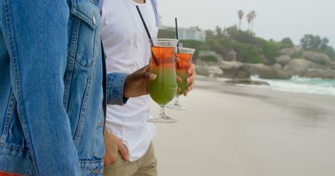 Couple Walking on Beach with Tropical Cocktails