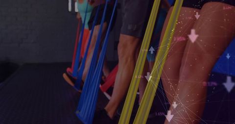 Group balancing on suspended fabric resistance bands during colorful studio fitness class