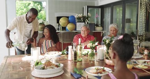 Multigenerational Diverse Family Gathering for Garden Dinner Sharing Roast, Wine, Candles