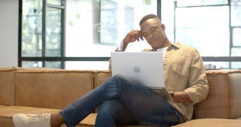 African american man using laptop in modern office environment