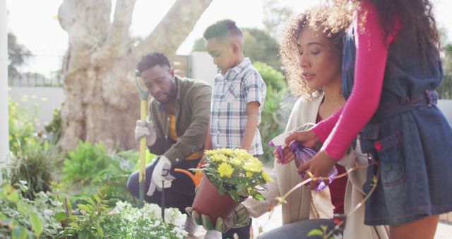 Family enjoying outdoor gardening activity in backyard on a sunny day. Parents and children engaging in planting and watering plants together. Useful for content related to family activities, outdoor bonding, gardening tips, and healthy lifestyles.