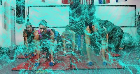 Group holding plank with dumbbells on red mats in fitness class building core strength