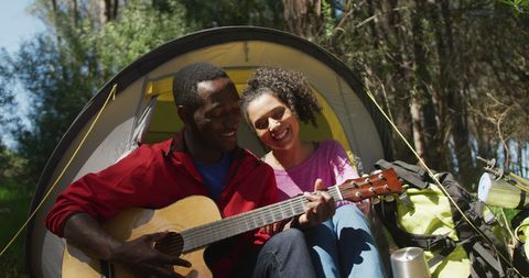 Couple Playing Guitar and Relaxing at Campsite in Wilderness