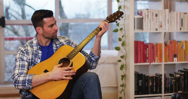 Handsome man playing guitar in living room at home
