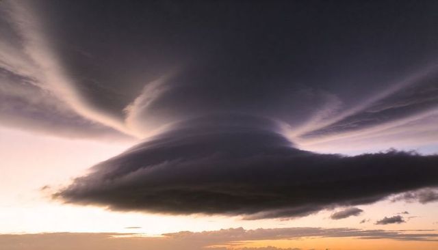 Layered lenticular cloud over sunset horizon creating dramatic disc formation
