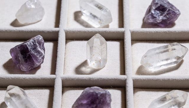 Clear quartz point standing in velvet compartment tray with amethyst grid display