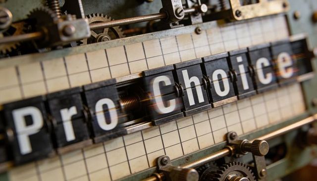 Rotating split-flap display spelling pro choice on vintage mechanical flipboard with gears