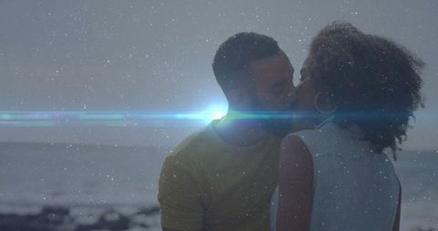 Romantic Couple Sharing Kiss on Rocky Shoreline at Dusk