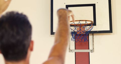 Person Preparing Shot at Basketball Hoop in Gym